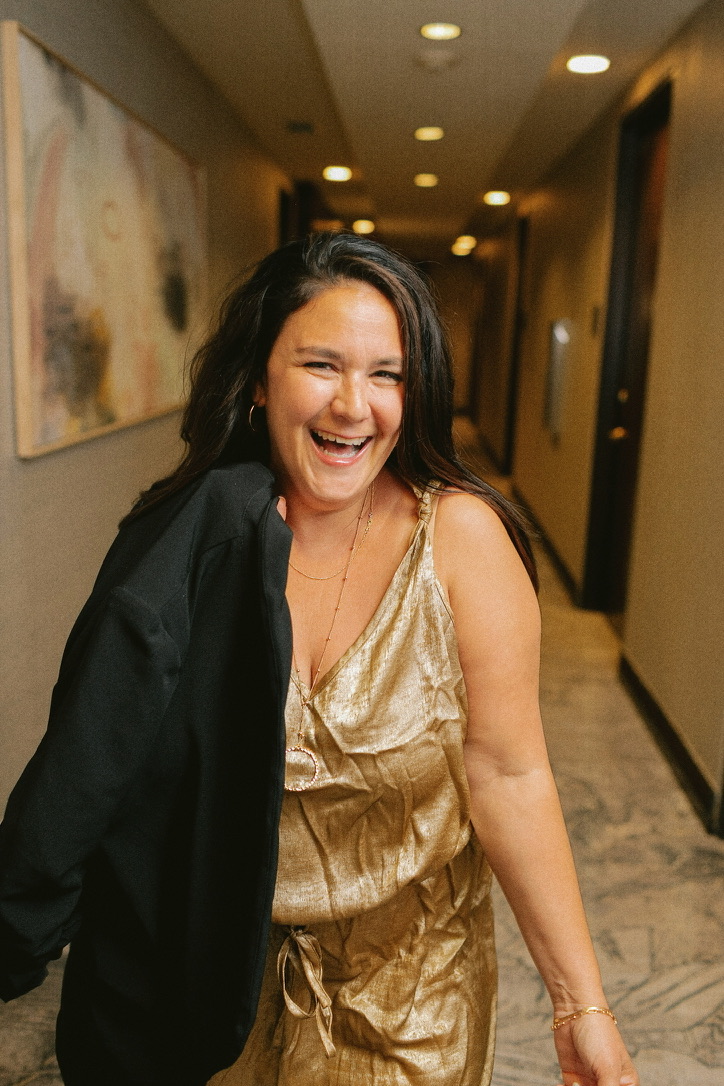 Aly Carter laughing mid-stride in a gold slip dress